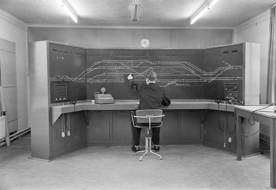 159684 Interieur van het seinhuis van de N.S. te Eindhoven, met de treindienstleider bij het NX-bedieningstableau.